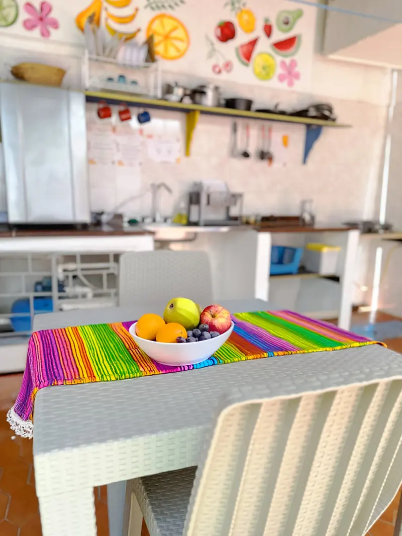 Mesa de la cocina con camino de mesa de rayas arcoíris y un plato de frutas