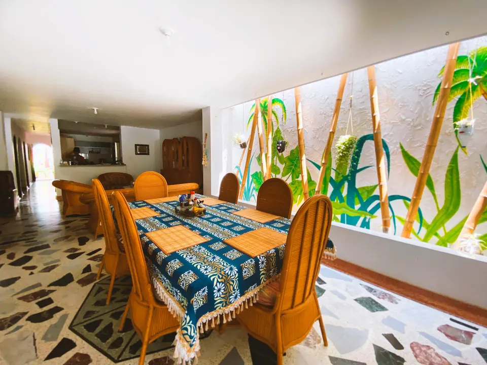 El comedor de la casa con su mural tropical y la sala al fondo