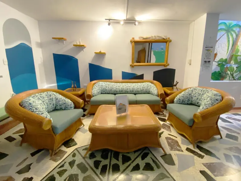 Rincón de la sala con sofás de mimbre, paneles azules en la pared y un espejo de marco pintado